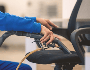 Deep cleaning an office chair with a high-powered vacuum.