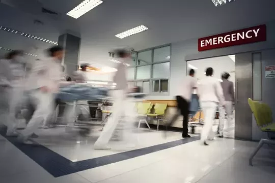 Blurred people walking through and into an emergency unit in a hospital.